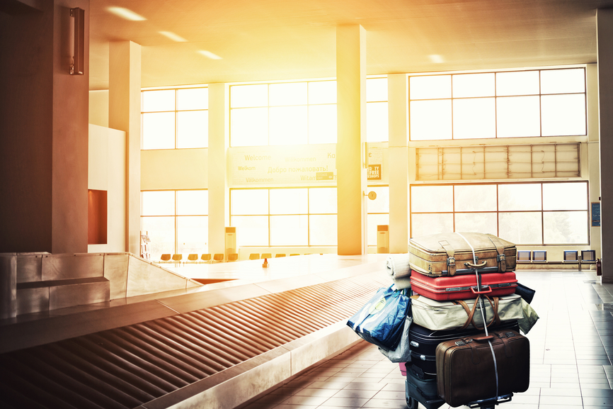 suitcases on a cart and carousel at airport