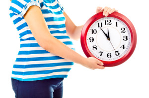 pregnant woman holding a clock waiting for baby