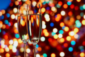 two champagne glasses with colorful lights in background