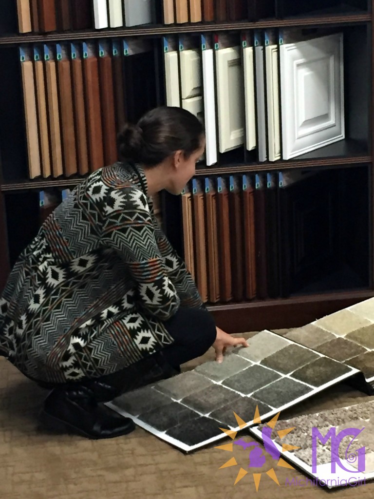 woman crouching down to check carpet samples at design center