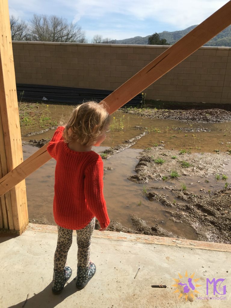 little girl staring at muddy backyard