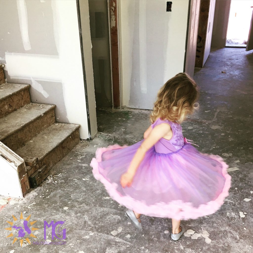 little girl twirling in a purple and pink dress at a new house construction site